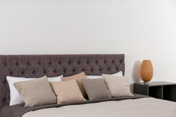 Large comfortable bed near light wall in modern room interior