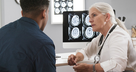Close up of female senior doctor explaining ct scans to patient after concussion. Portrait of black...