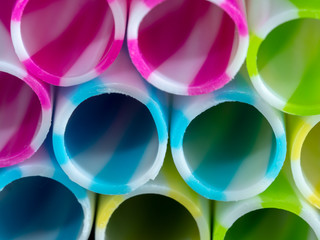 Colourly striped plastic drinking straws, black underground background