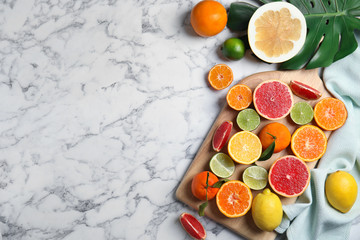 Different citrus fruits on marble background, top view. Space for text