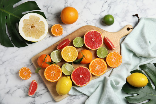 Different citrus fruits on marble background, top view