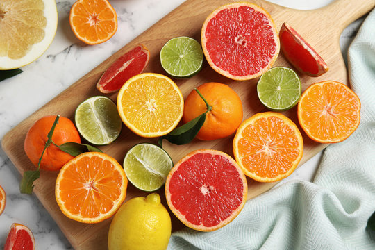 Different citrus fruits on marble background, top view