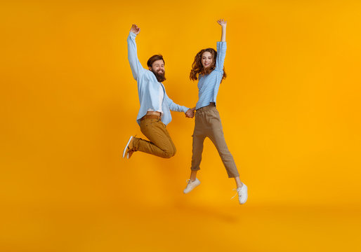 couple of emotional people man and woman jumping on yellow background.