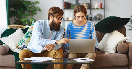 married couple with bills receipts documents and laptop at home
