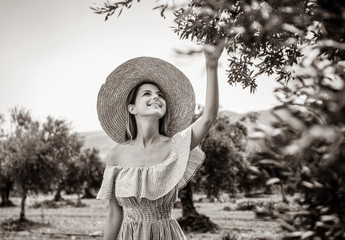 Young redhead girl wearing in dress and hat have a rest in greek olive garden in Heraklion, Crete, Greece