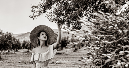 Young redhead girl wearing in dress and hat have a rest in greek olive garden in Heraklion, Crete,...