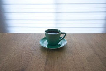 green cup and coffee on wood table