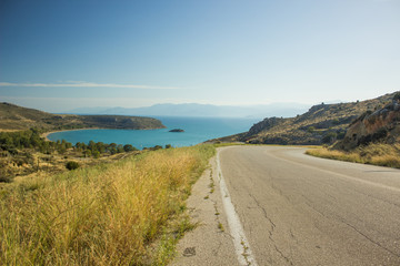 empty curved old car road in dry summer yellow highland nature environment  landscape with sea bay background view