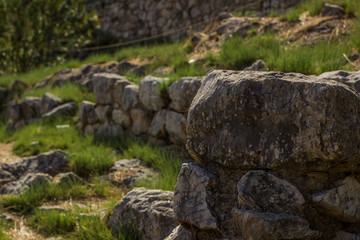 soft focus stone foreground on unfocused abandoned ruin of ancient city in small green grass meadow, exterior landscape design