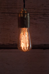 close-up of old lit bulb, worn wooden background