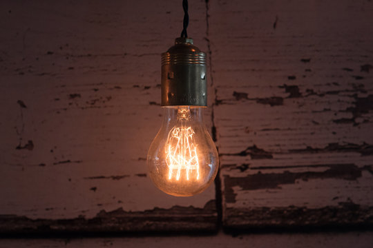 close-up of old lit bulb, worn wooden background