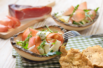 Südtiroler Salat mit Speck, Mozzarelline und Rucola mit Schüttelbrot serviert - South Tyrolean salad with bacon, mozzarella pearls and rocket served with crunchy rye bread 