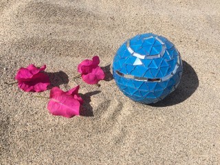 Fototapeta na wymiar Blue ball with pink flowers on sand