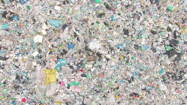 AERIAL TOP DOWN: View from above of a stinky heap of garbage in a plastic sorting site. Flying above a pile of waste in an industrial landfill near big city. Concerning aerial view of endless rubbish.
