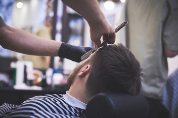 Razor in foreground hands of barber. Concept barbershop for men.
