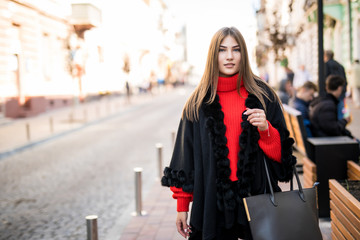 Fashion style portrait of young trendy girl walking along the street