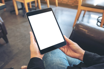 Mockup image of a woman holding black tablet pc with blank white screen while sitting in cafe