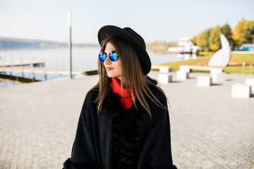 Smiling young girl wearing a black hat, sunglasses in the park