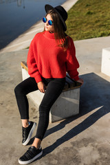 Fototapeta premium Young beauty Girl in black hat sitting on a bench near lake in city park