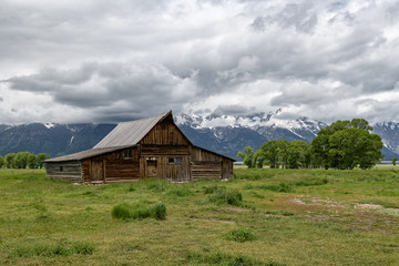 Obraz premium Old mormon barn in Grand Teton Mountains with low clouds. Grand Teton National Park, Wyoming, USA.
