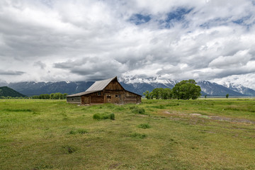 Obraz premium Old mormon barn in Grand Teton Mountains with low clouds. Grand Teton National Park, Wyoming, USA.