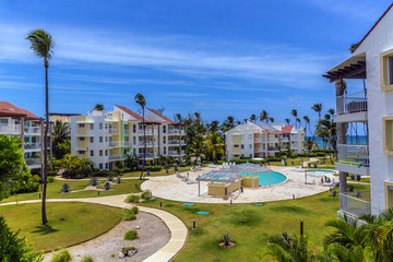 Obraz premium A beach front gate community with a large swimming pool in a blue sky day in Punta Cana, Dominican Republic