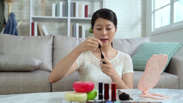 Young beauty blogger recording video indoors teaching makeup tutorial online streaming. asian woman vlogger showing mascara in live at home. beautiful female chinese talking to camera introducing.