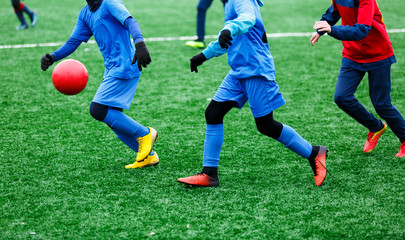 Obraz na płótnie Canvas Two young Footballers in red and blue sportswear running,dribble and competing for ball. Junior football match competition. Winter activities, soccer game, training concept