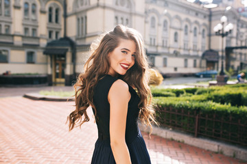 Portrait from back of elefant girl with long curly hair walking on steer on old building...
