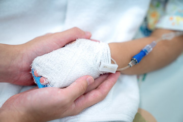 Hand of mother and baby with saline