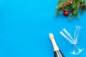 new year design with spruce, champagne bottle and glasses blue table background top view space for text