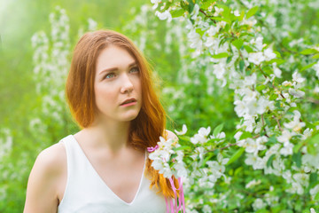 Large portrait of a young girl in the open air near a flowering tree. Spring and flowers.