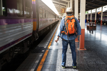 Asian traveler man with belongings waiting for travel by train at Chiang Mai train station, Thailand