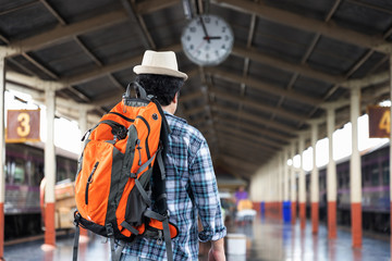 Asian traveler man with belongings waiting for travel by train at Chiang Mai train station, Thailand