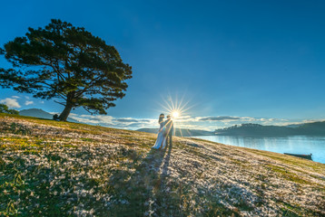 Da Lat, Vietnam - November 29th, 2018: Silhouette of happy lovers together to welcome the dawn on the pink grass in the romantic morning sun in the highlands of Da Lat, Vietnam