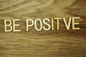 Be Positive text message on wooden background