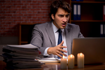 Businessman working late in office with candle light