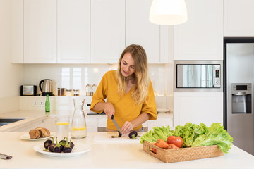 Blonde woman making lunch on a white kitchen at home