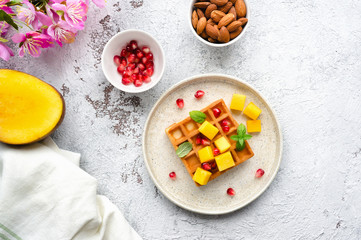 Sweet breakfast with homemade waffles, fresh mango, pomegranate and mint. 