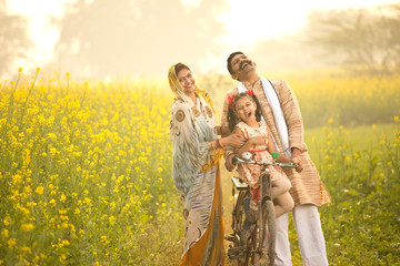 Rural Indian family with bicycle in agricultural field
