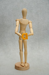 A wooden mannequin holding a letter a