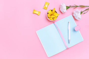workspace desk styled design office supplies, candy and white flower on pink pastel background minimal style