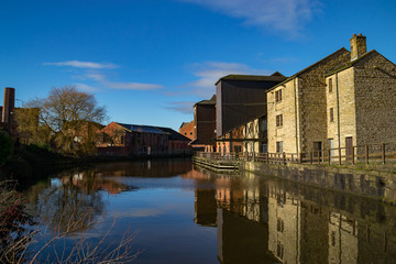Old buildings on the side of the Leeds/ Liverpool Canal as the morning sun rises.  Wigan Pier, Wigan, England