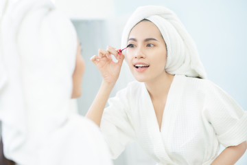 Asian beautiful women applying black mascara eyelashes after bathing