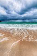 Storm on a tropical beach, dark thunderclouds, beautiful spectacular landscape, waves and white sand, climate change