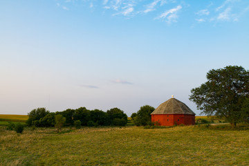 Red round barn in the open field in the late afternoon light.  LaSalle County, Illinois, USA