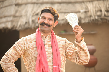 Excited farmer holding Indian rupee notes and screaming