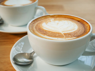Cup of latte art coffee on wooden table