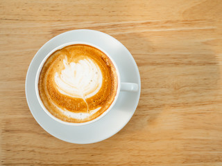 Cup of latte art coffee on wooden table, top view