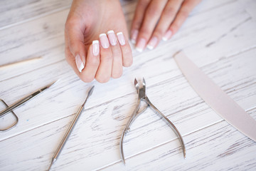 Manicure. Close up female hands situating on desk near nail tools